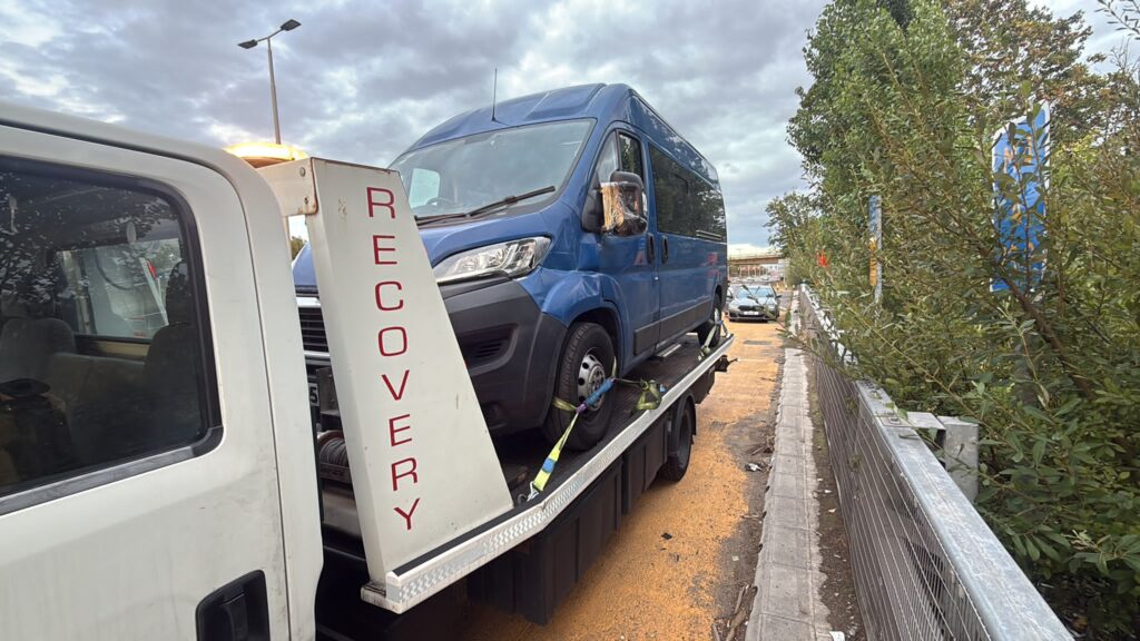 Blue van secured on a flatbed recovery truck