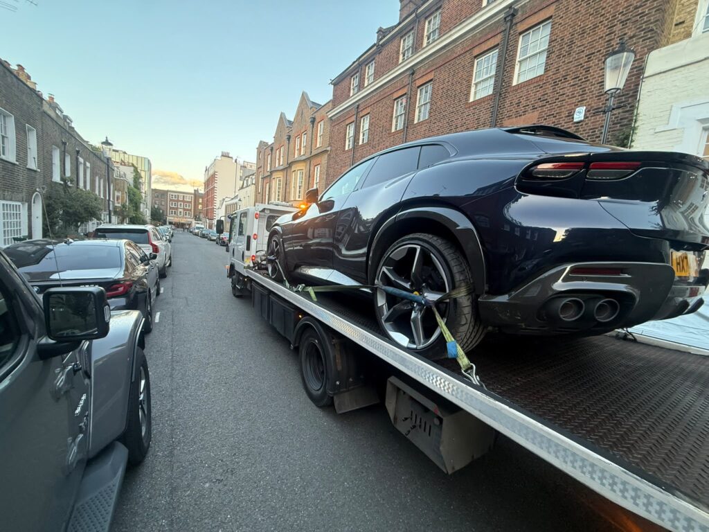 Black SUV secured on a flatbed recovery truck
